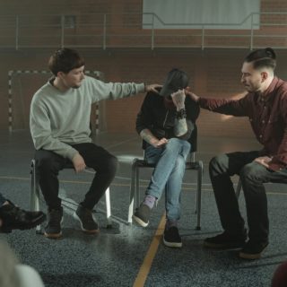 men holding shoulders of a person sitting in the middle of them