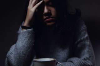 woman grabbing her head on darkness