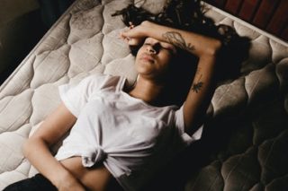woman lying in bed with her arm on her forehead