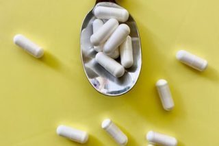 spoon with withe pills over a yellow background