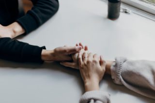 person in black long sleeve shirt holding hand with person in white