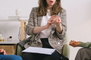 Female therapist during group session talking to female patients gathering in light cozy office