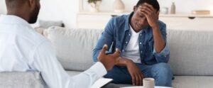 Depressed black man talking to psychologist during individual therapy