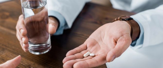 doctor giving pills and water to patient