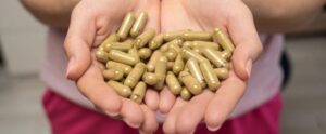 Handful of green kratom pills in woman hands