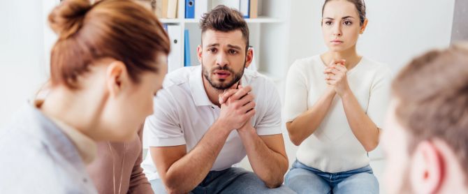 People sitting on chairs and having group therapy meeting