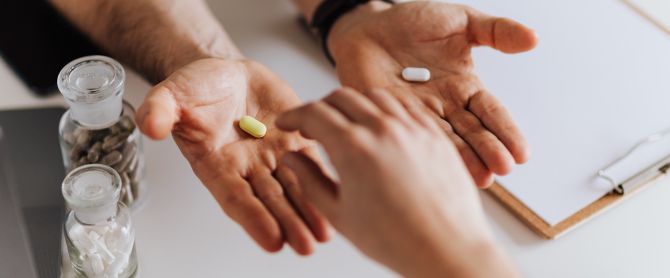 hands exchanging pills in a clinical environment