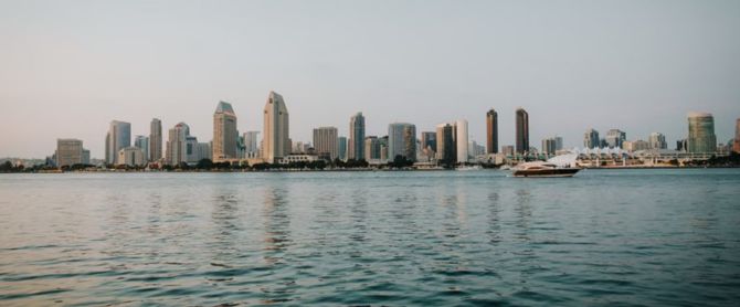 San Diego skyline reflecting on the bay with a yacht cruising by
