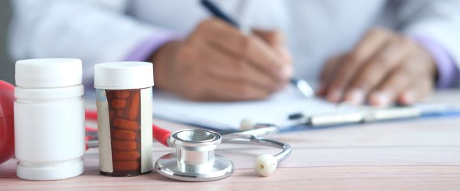 doctor writing prescription with medicines