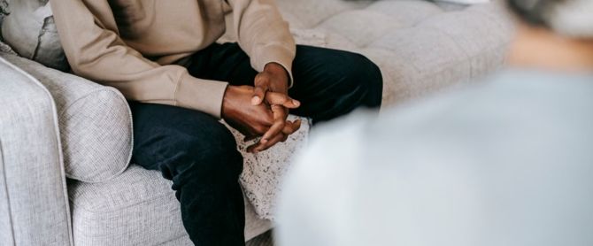 A therapy session with a focus on a man's clasped hands