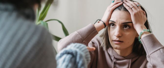 A woman in a beige hoodie looks distressed
